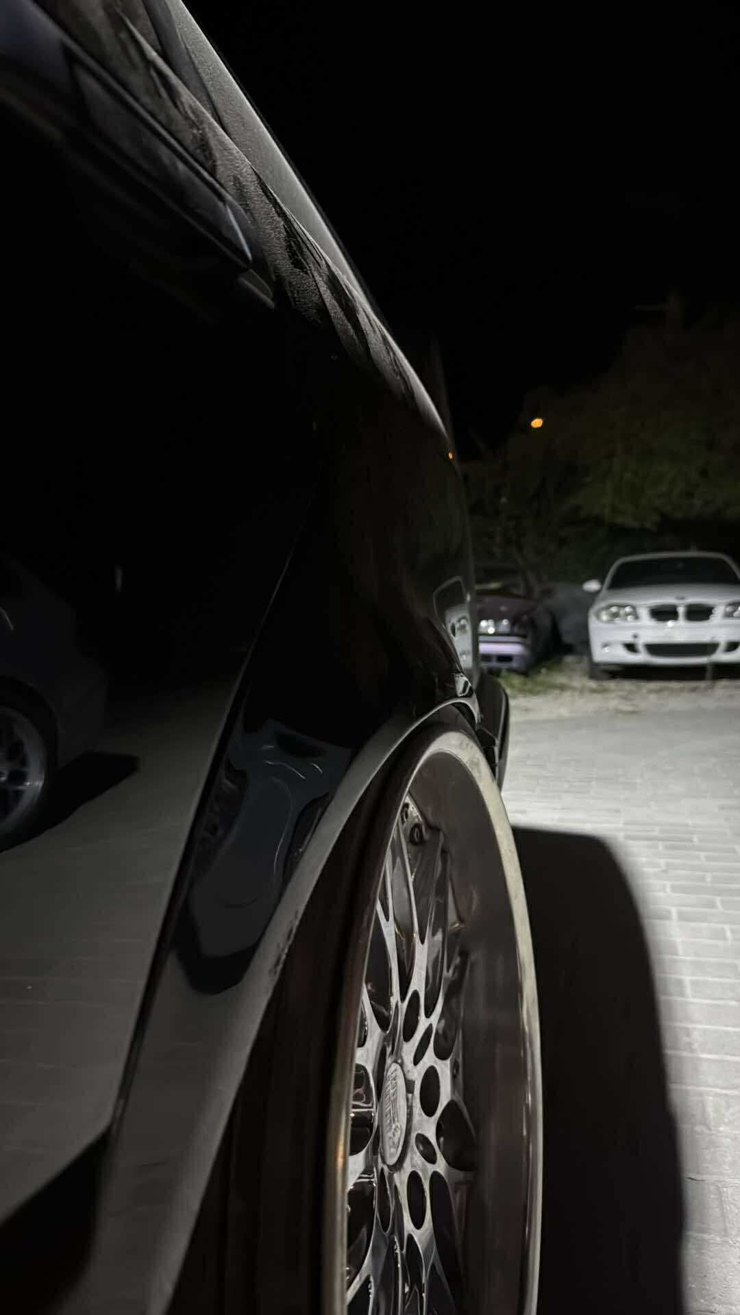 Zbliżenie felgi BMW i auta zaparkowane w tle nocą